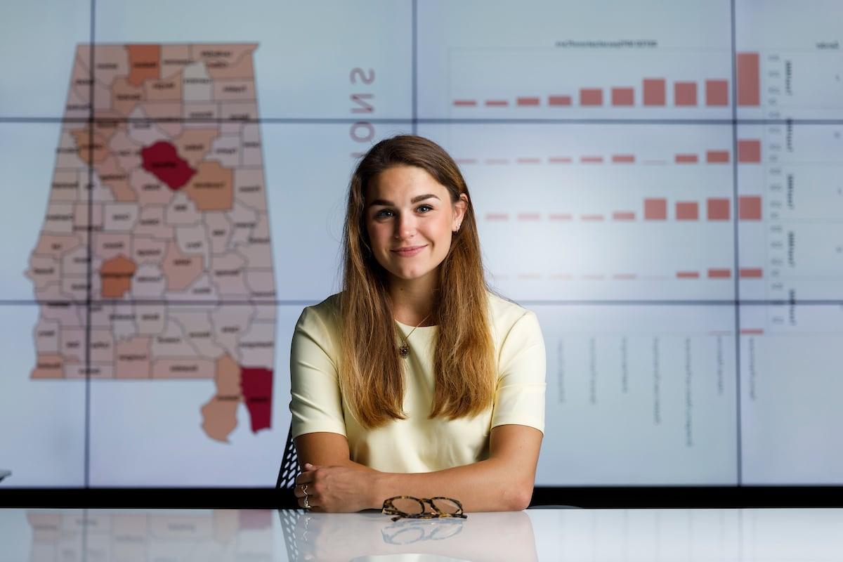 A student sits in front of a research project displayed on a video wall